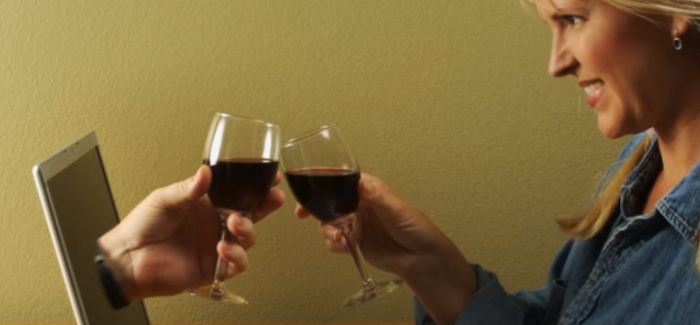 man drinking wine in front of laptop